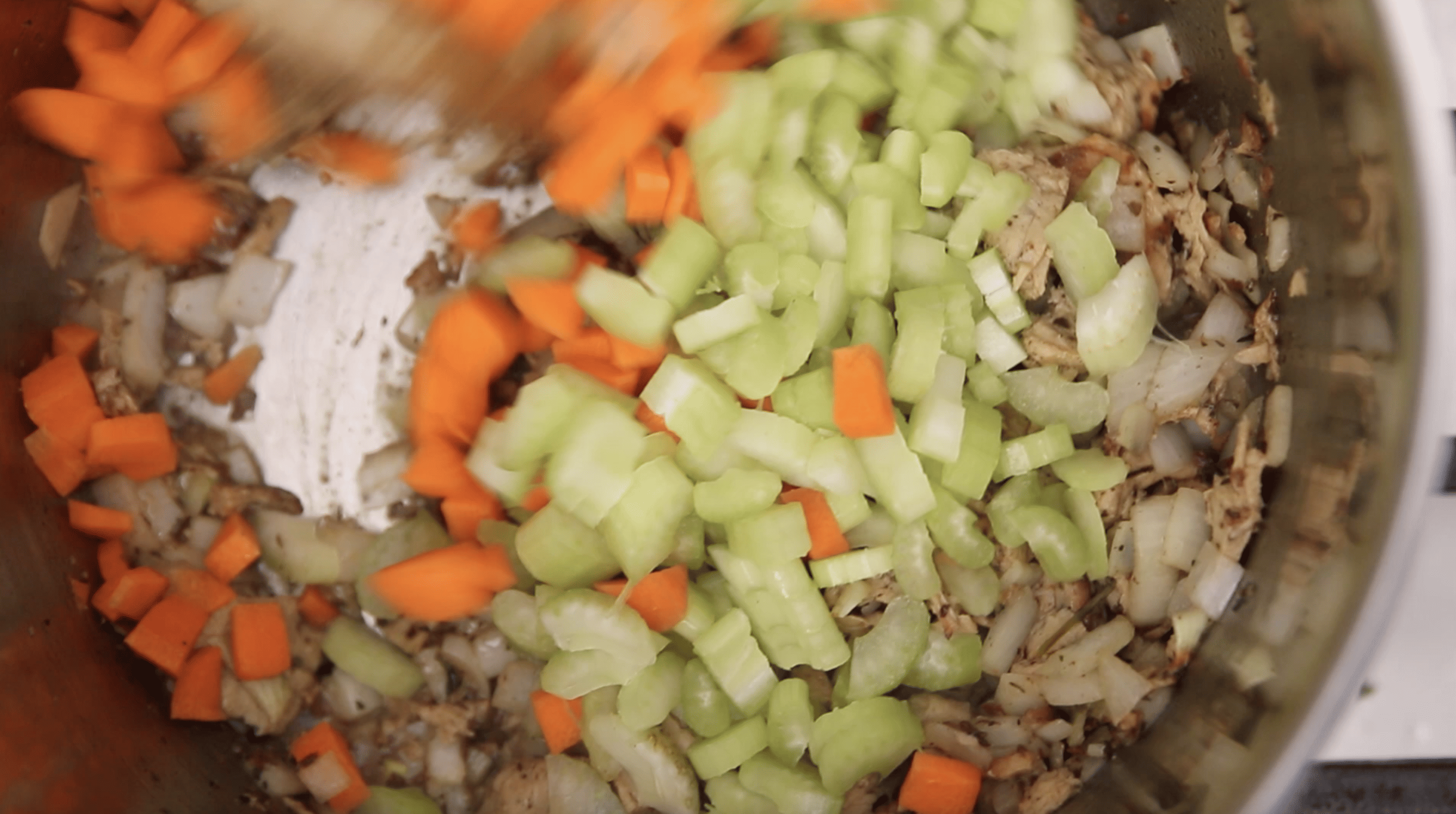 adding celery and carrot to the pot of soup