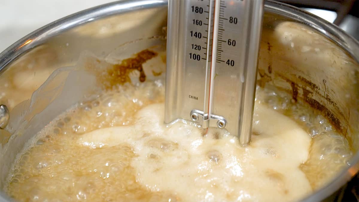 sauce pan with caramel bubbling and a thermometer in the pan