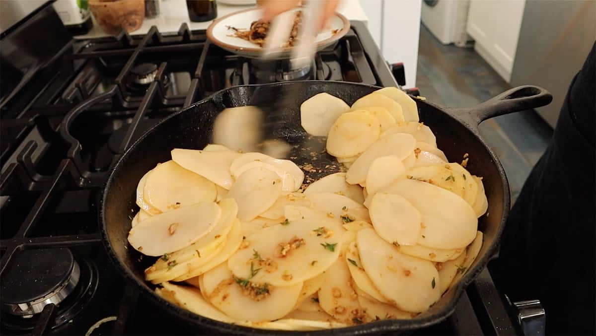 a cast iron skillet with sliced potatoes in it