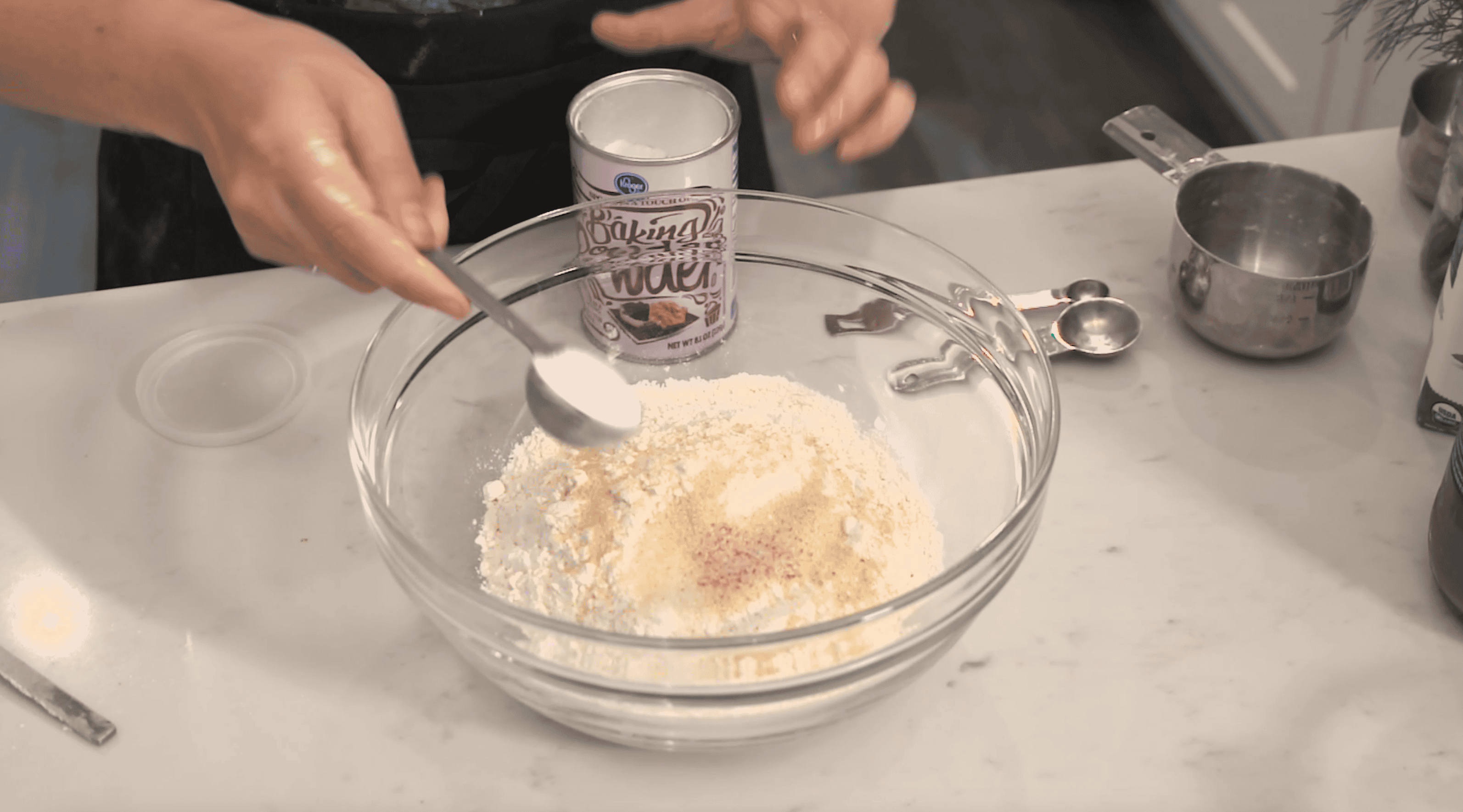 baking soda being added to a bowl of flour and other dry ingredients