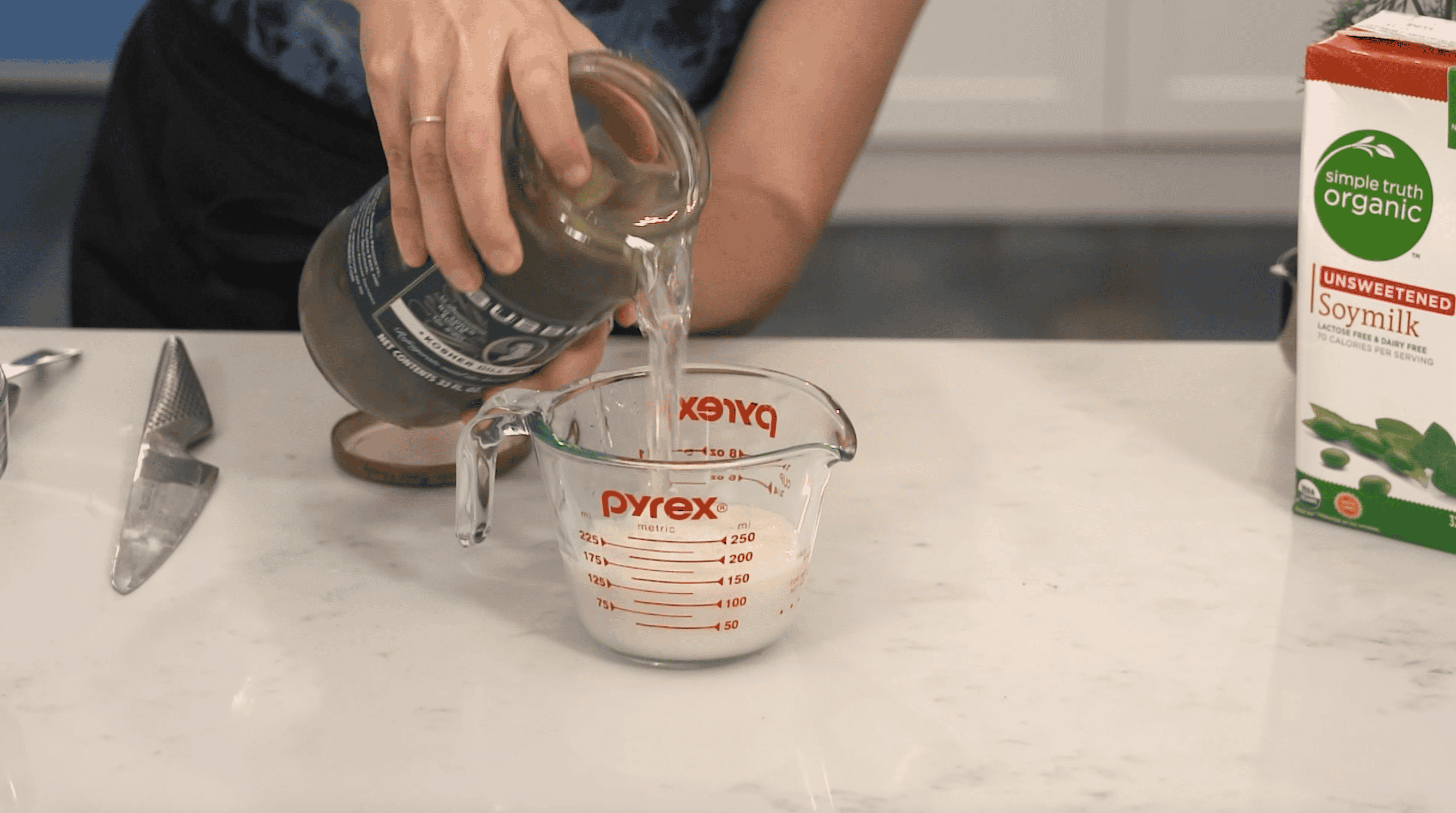 pickle juice being added to a measuring cup with soy milk