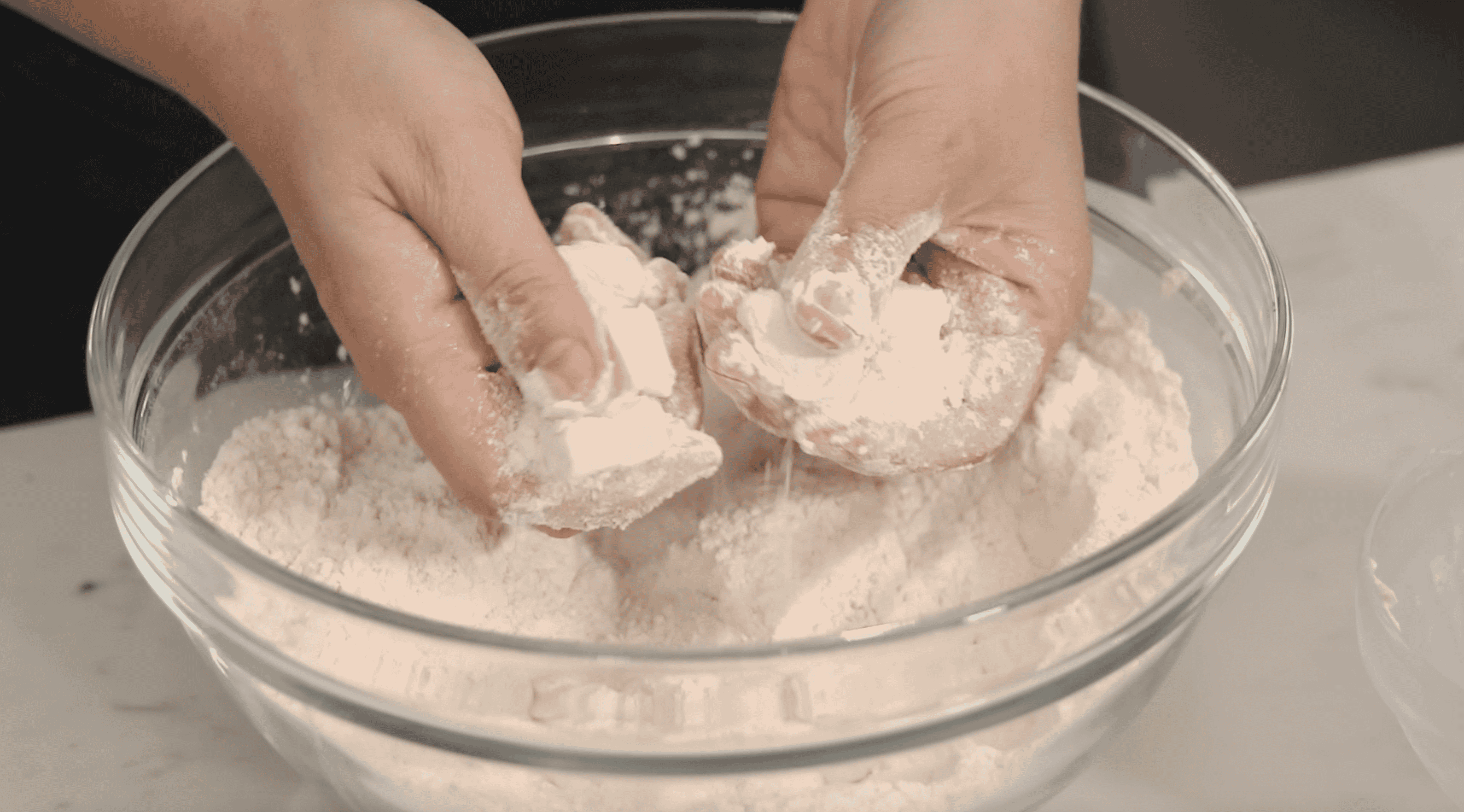 butter cubes being pinched into dry ingredeints to form a ragged dough