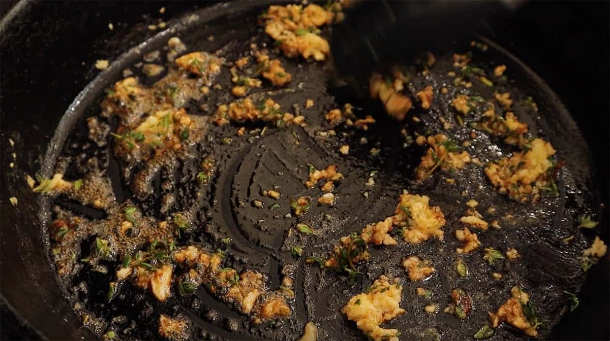 a cast iron skillet sauteing garlic and thyme