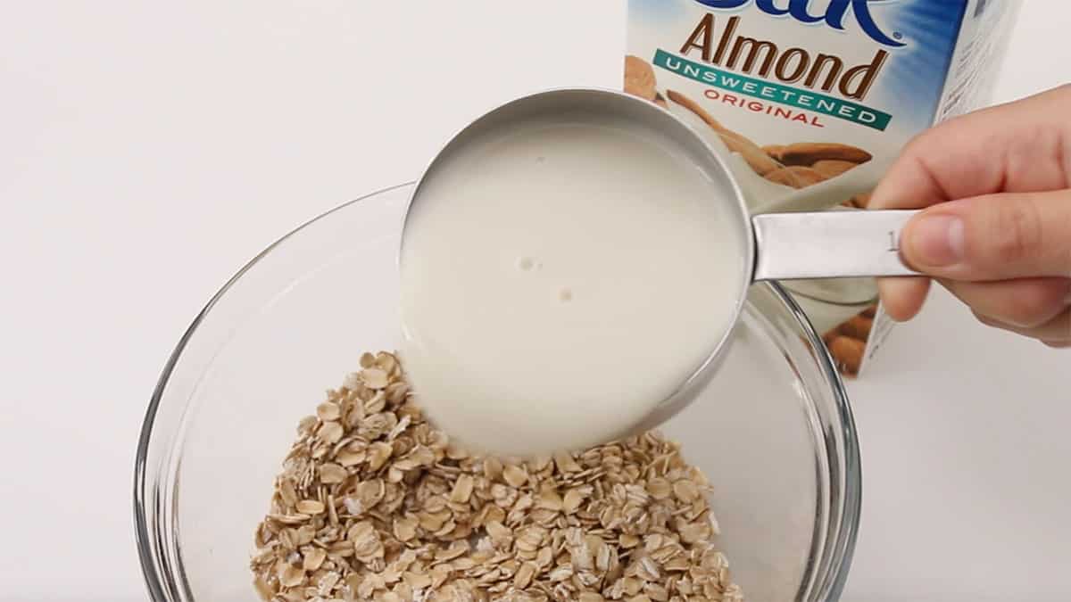mixing bowl with rolled oats and milk being poured in