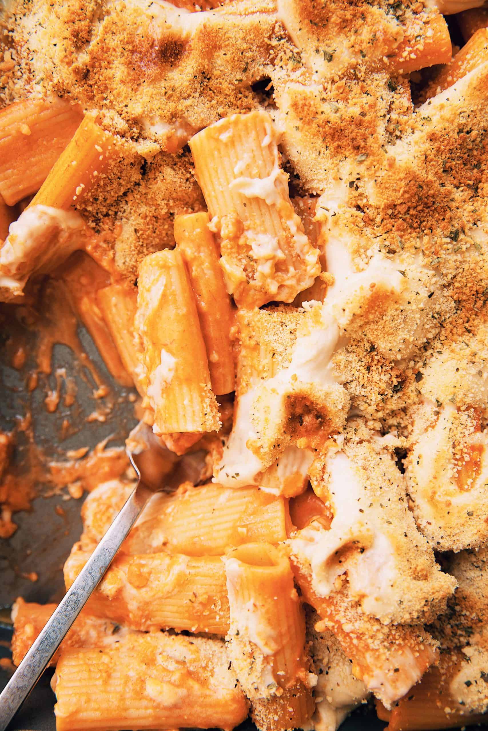 close up of a fork digging into a tray of vegan baked gochujang rigatoni