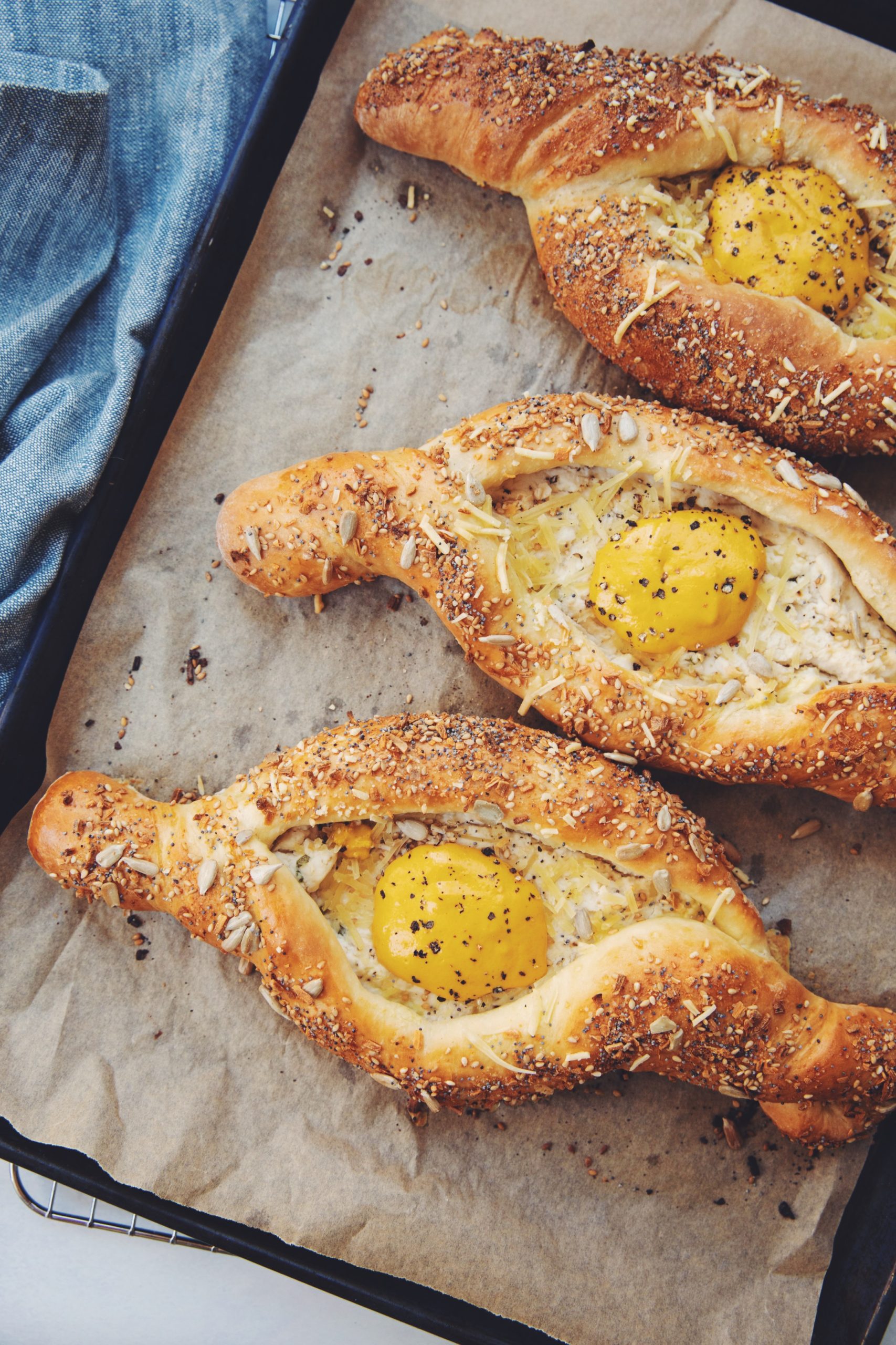 four vegan khachapuri boats on parchment lined baking sheet, finished with everything topping